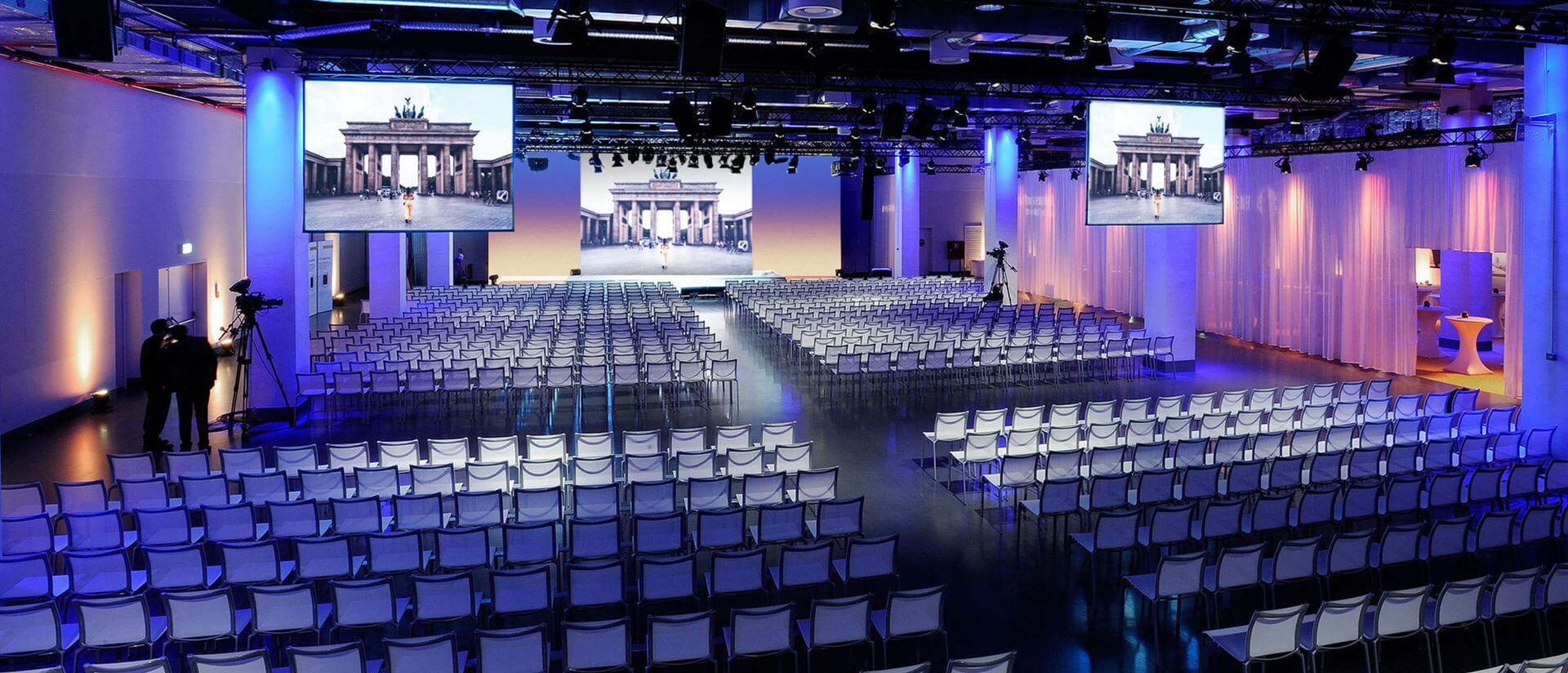 reef berlin event area with blue lighting and set seating with a screen